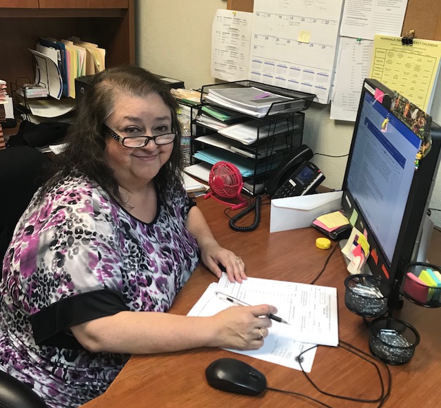 Mary Lonzano. Paralegal sitting at a desk in front of a computer