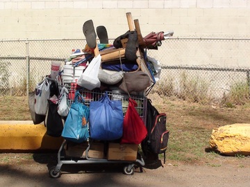 Homeless person's shopping cart filled w/belongings