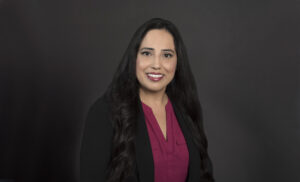 Portrait of woman wearing suit jacket and maroon blouse.