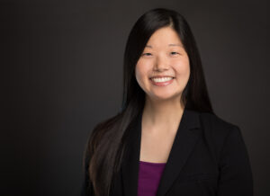 Portrait of woman wearing suit jacket and maroon blouse.